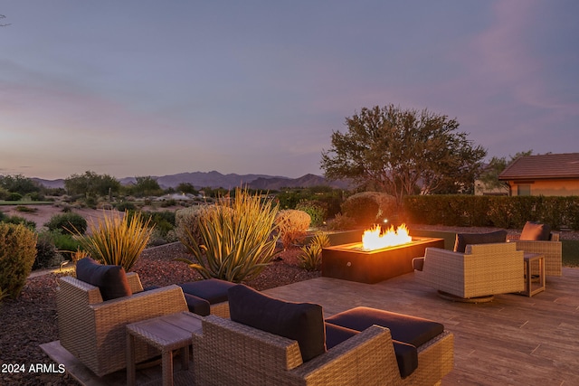 patio terrace at dusk with a deck with mountain view and an outdoor living space with a fire pit