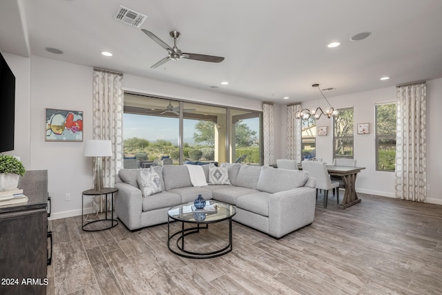 living room with ceiling fan with notable chandelier, a wealth of natural light, and light hardwood / wood-style floors