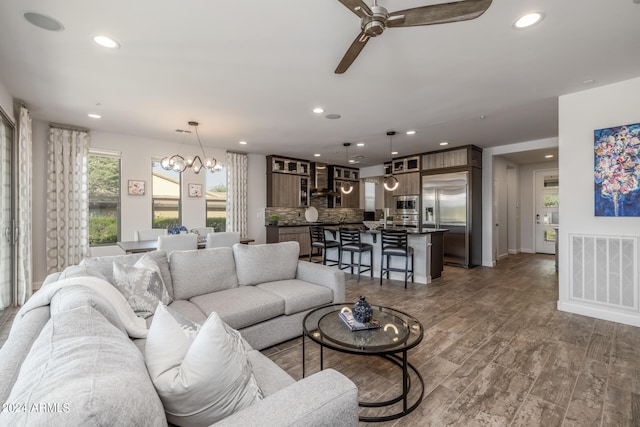 living room with ceiling fan with notable chandelier and hardwood / wood-style floors