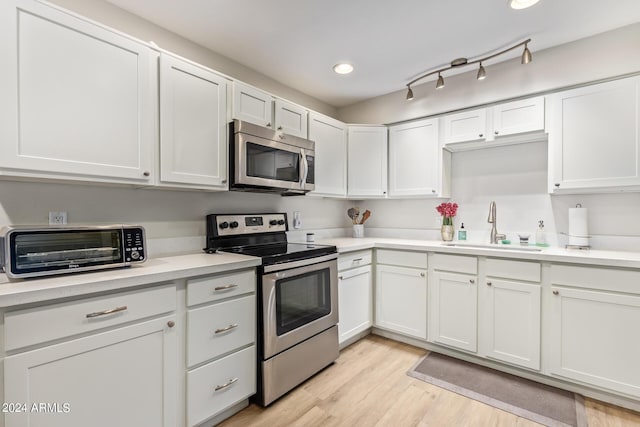 kitchen featuring light hardwood / wood-style floors, sink, white cabinetry, and stainless steel appliances