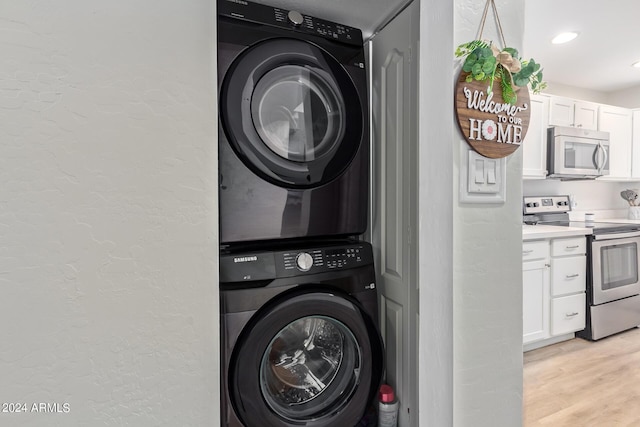 laundry area featuring light hardwood / wood-style floors and stacked washer / drying machine