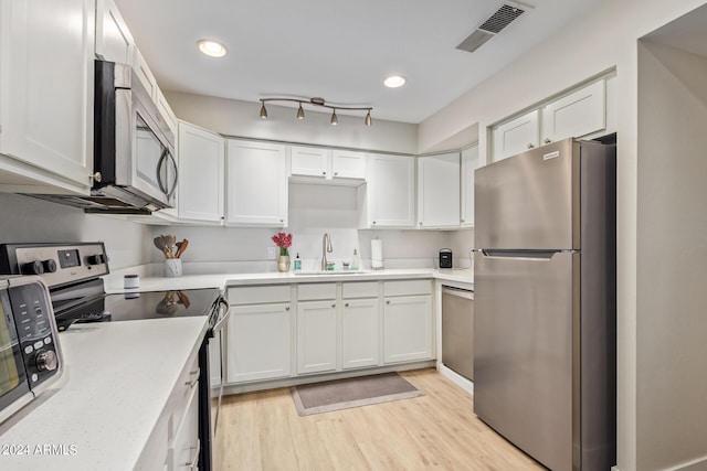 kitchen with sink, light hardwood / wood-style floors, white cabinetry, and appliances with stainless steel finishes