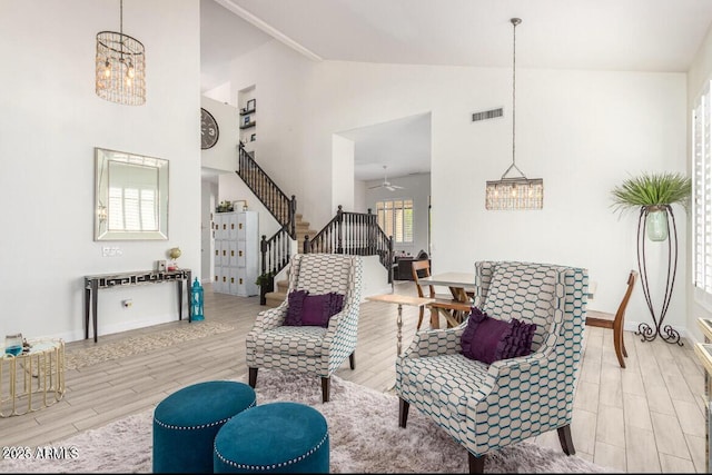 living room with a notable chandelier, light hardwood / wood-style flooring, and high vaulted ceiling