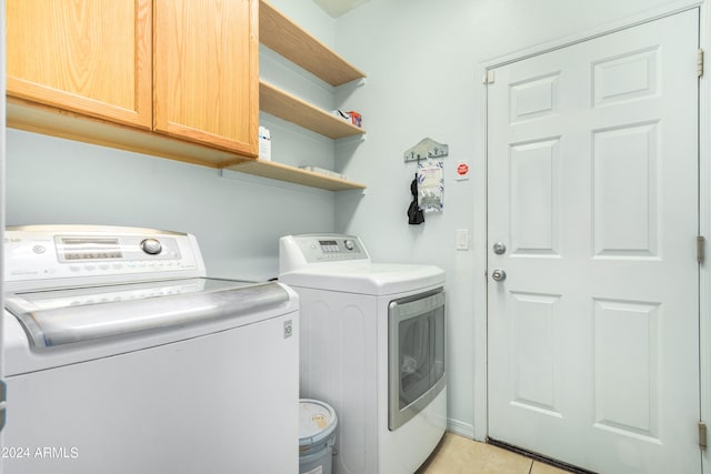 laundry room with separate washer and dryer, light tile patterned flooring, and cabinets