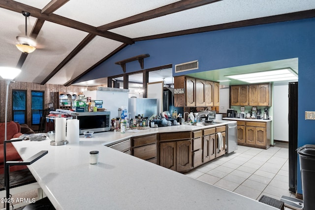 kitchen featuring light tile patterned flooring, lofted ceiling with beams, a textured ceiling, appliances with stainless steel finishes, and kitchen peninsula