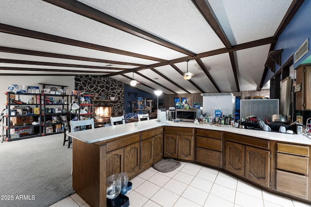 kitchen with vaulted ceiling with beams, dark brown cabinetry, a fireplace, a textured ceiling, and kitchen peninsula