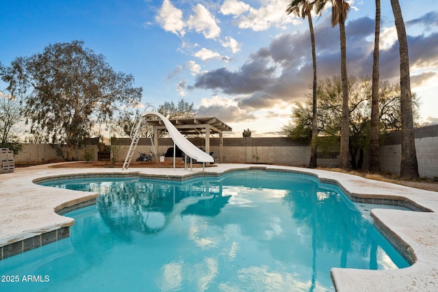 pool at dusk featuring a water slide