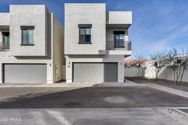 view of front of house with an attached garage, fence, and stucco siding