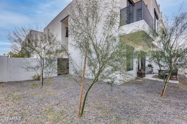 view of property exterior with a patio, fence, and stucco siding