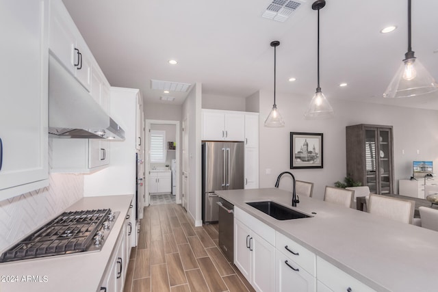 kitchen with hanging light fixtures, backsplash, appliances with stainless steel finishes, sink, and white cabinets