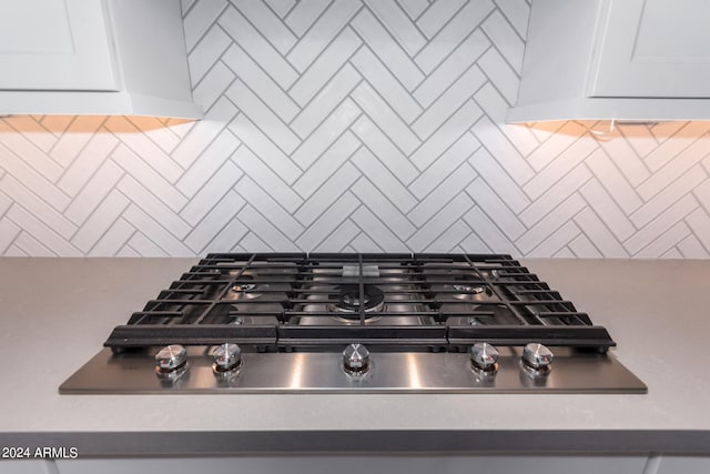 details featuring backsplash and stainless steel gas cooktop