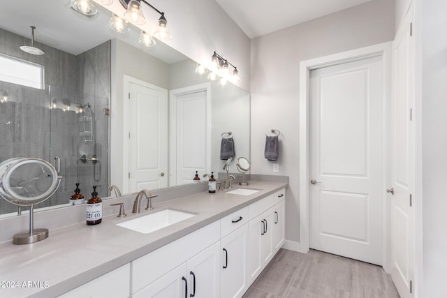 bathroom with dual sinks, hardwood / wood-style floors, an enclosed shower, and vanity with extensive cabinet space