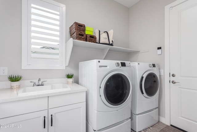 washroom with washing machine and clothes dryer, cabinets, and sink