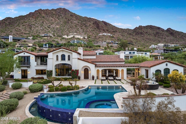 back of property featuring a tile roof, a chimney, a mountain view, and a patio