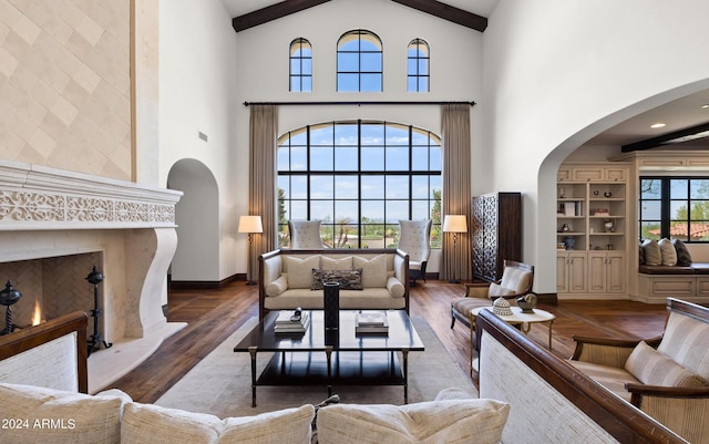 living room with baseboards, arched walkways, wood finished floors, a lit fireplace, and beam ceiling