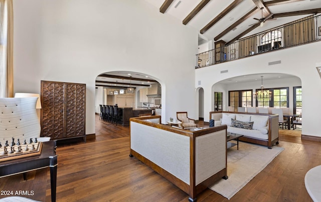 living room with visible vents, arched walkways, wood-type flooring, beam ceiling, and ceiling fan with notable chandelier