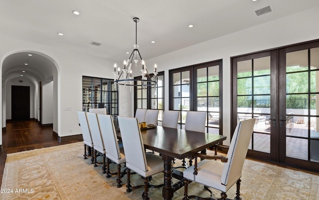 dining space featuring arched walkways, visible vents, plenty of natural light, and wood finished floors