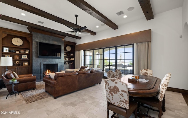 living room with built in shelves, visible vents, a tile fireplace, beamed ceiling, and baseboards