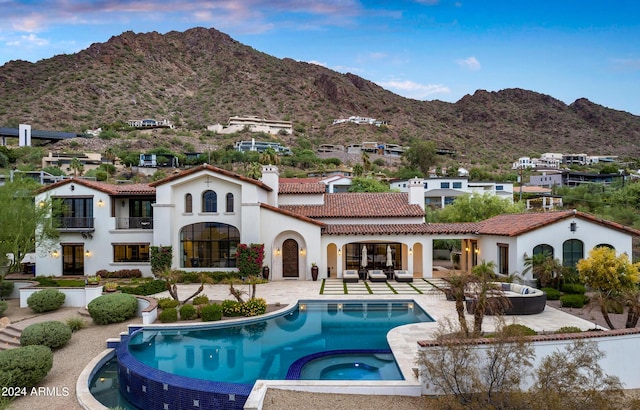 back of house with a patio area, a tile roof, a chimney, and a mountain view