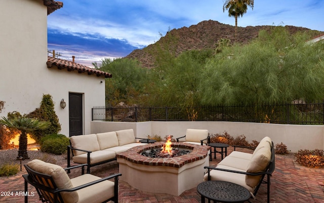 view of patio with an outdoor living space with a fire pit, fence, and a mountain view