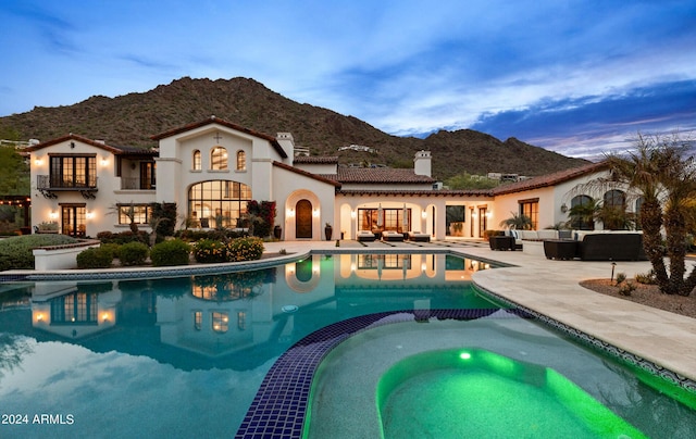 view of swimming pool with a patio area, a pool with connected hot tub, a mountain view, and an outdoor living space