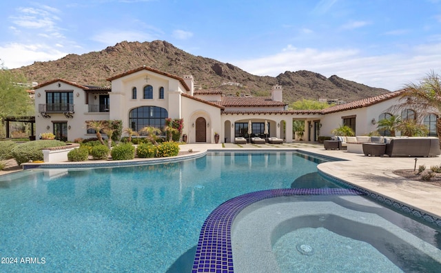 view of swimming pool with a pool with connected hot tub, a mountain view, outdoor lounge area, and a patio