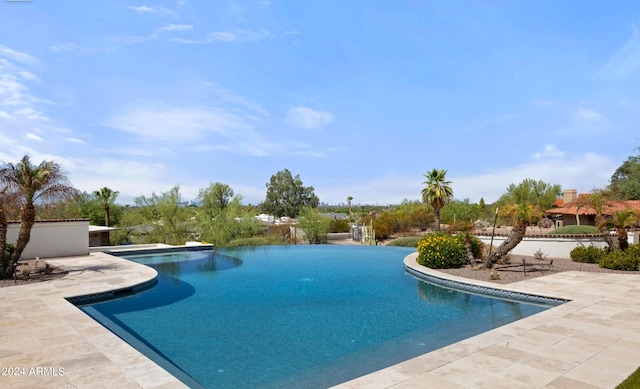 view of swimming pool with an infinity pool and a patio area