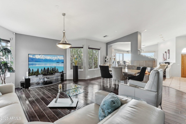 living room with visible vents, vaulted ceiling, baseboards, and wood finished floors