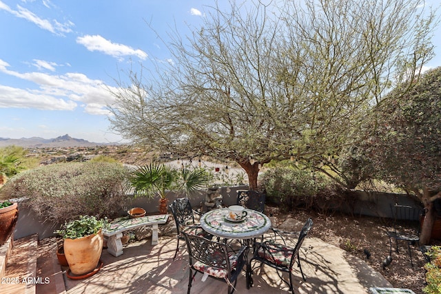 view of patio / terrace featuring outdoor dining space, a mountain view, and fence