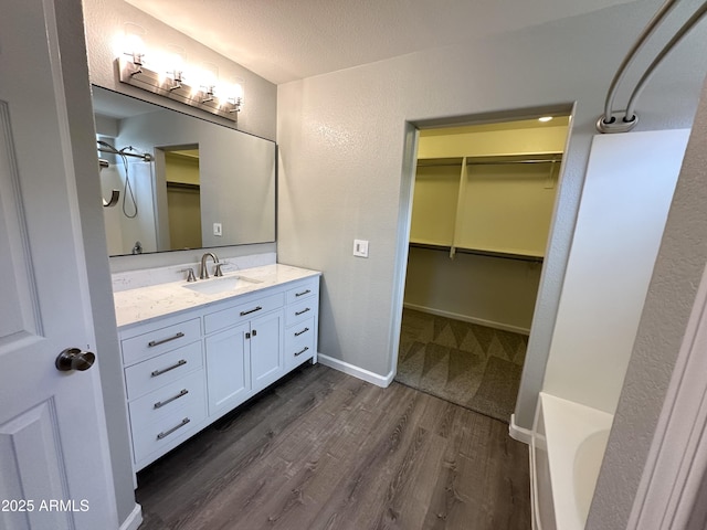 8514 S 49th Dr, Laveen, AZ 85339 - bathroom featuring vanity, a spacious closet, wood finished floors, a tub, and a textured ceiling