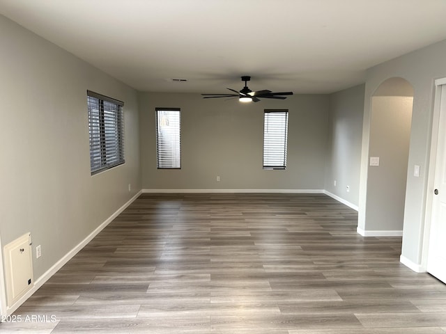 8514 S 49th Dr, Laveen, AZ 85339 - empty room featuring a ceiling fan, arched walkways, baseboards, and wood finished floors