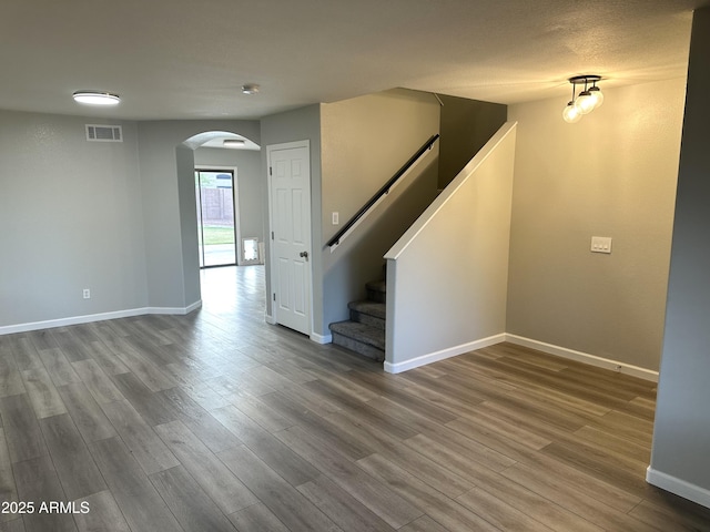 8514 S 49th Dr, Laveen, AZ 85339 - unfurnished living room featuring arched walkways, wood finished floors, baseboards, and stairs