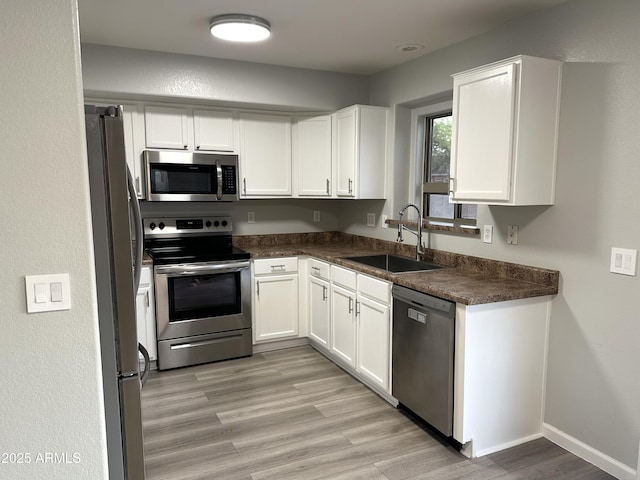 8514 S 49th Dr, Laveen, AZ 85339 - kitchen featuring appliances with stainless steel finishes, a sink, white cabinets, dark countertops, and light wood finished floors