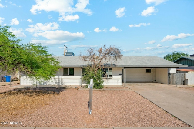 ranch-style house featuring fence, an attached carport, and driveway