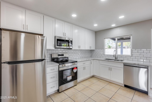 kitchen with light tile patterned flooring, sink, white cabinetry, appliances with stainless steel finishes, and decorative backsplash