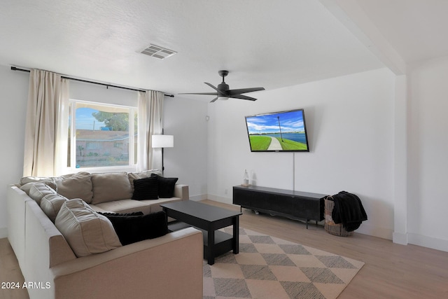 living room featuring ceiling fan, beam ceiling, and light wood-type flooring