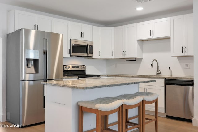 kitchen featuring white cabinets, light stone countertops, light wood-type flooring, and appliances with stainless steel finishes