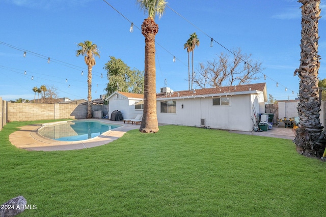 rear view of property featuring a lawn and a fenced in pool