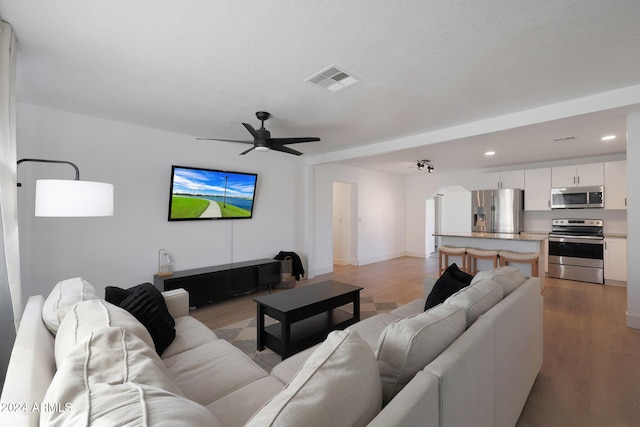 living room with ceiling fan and light hardwood / wood-style flooring