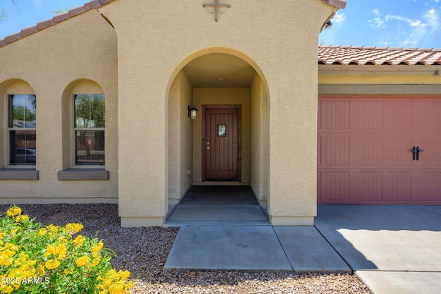 view of exterior entry with a tile roof and stucco siding
