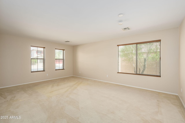empty room with baseboards, visible vents, and light colored carpet