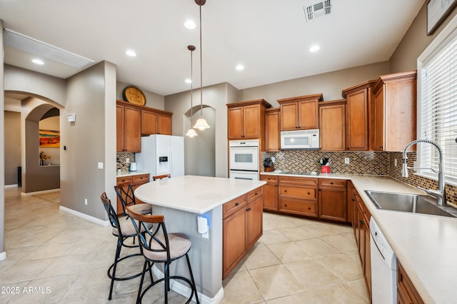 8417 W Northview Ave, Glendale, AZ 85305 - kitchen featuring white appliances, arched walkways, a center island, a sink, and brown cabinetry