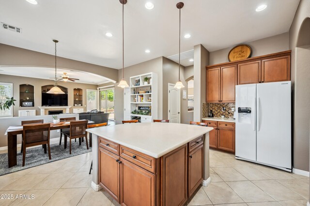 8417 W Northview Ave, Glendale, AZ 85305 - kitchen featuring white refrigerator with ice dispenser, arched walkways, brown cabinets, a center island, and ceiling fan