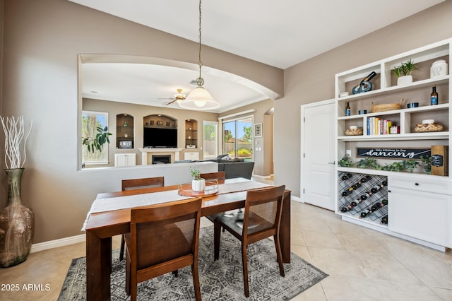 8417 W Northview Ave, Glendale, AZ 85305 - dining space featuring arched walkways, a ceiling fan, light tile patterned floors, and a fireplace