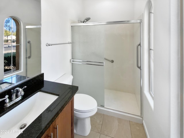 bathroom with tile patterned flooring, vanity, toilet, and a shower with shower door