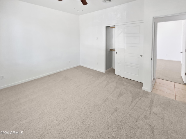 unfurnished bedroom featuring ceiling fan, a closet, and light colored carpet