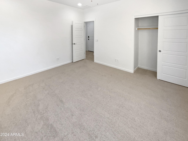 unfurnished bedroom featuring light colored carpet and a closet