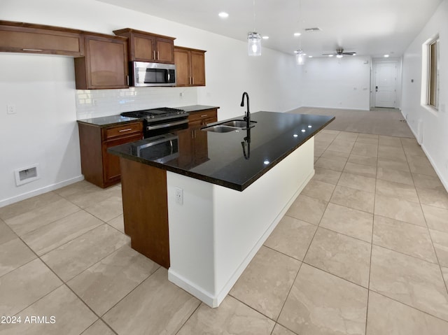 kitchen with a center island with sink, ceiling fan, sink, and stainless steel appliances