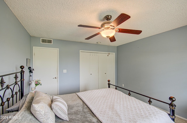 carpeted bedroom featuring a closet, ceiling fan, and a textured ceiling