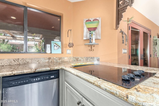 kitchen featuring light stone counters, black electric cooktop, and stainless steel dishwasher